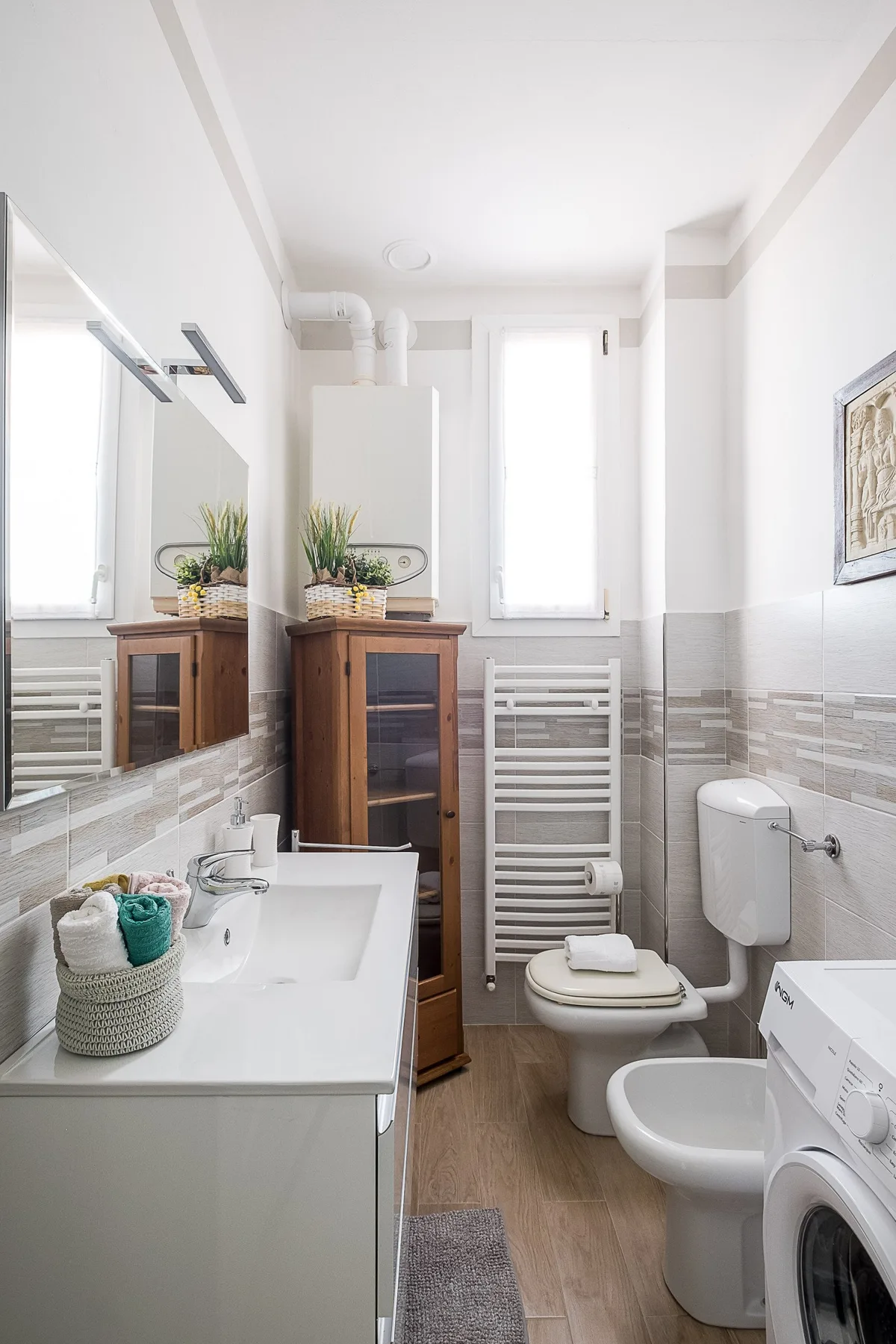 A bright bathroom with a vanity, toilet, bidet, and washing machine.