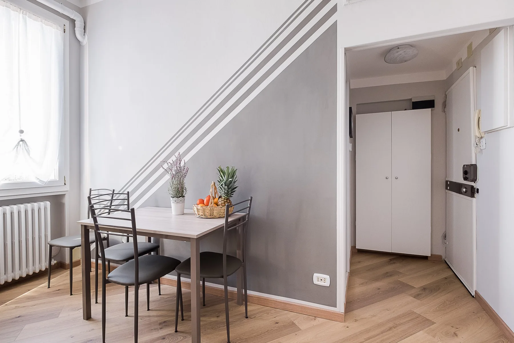 A dining area with a table and chairs sits beside a bright window.