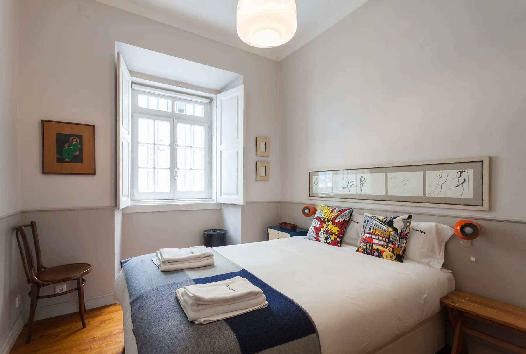Un dormitorio con una cama, toallas dobladas y una ventana luminosa.