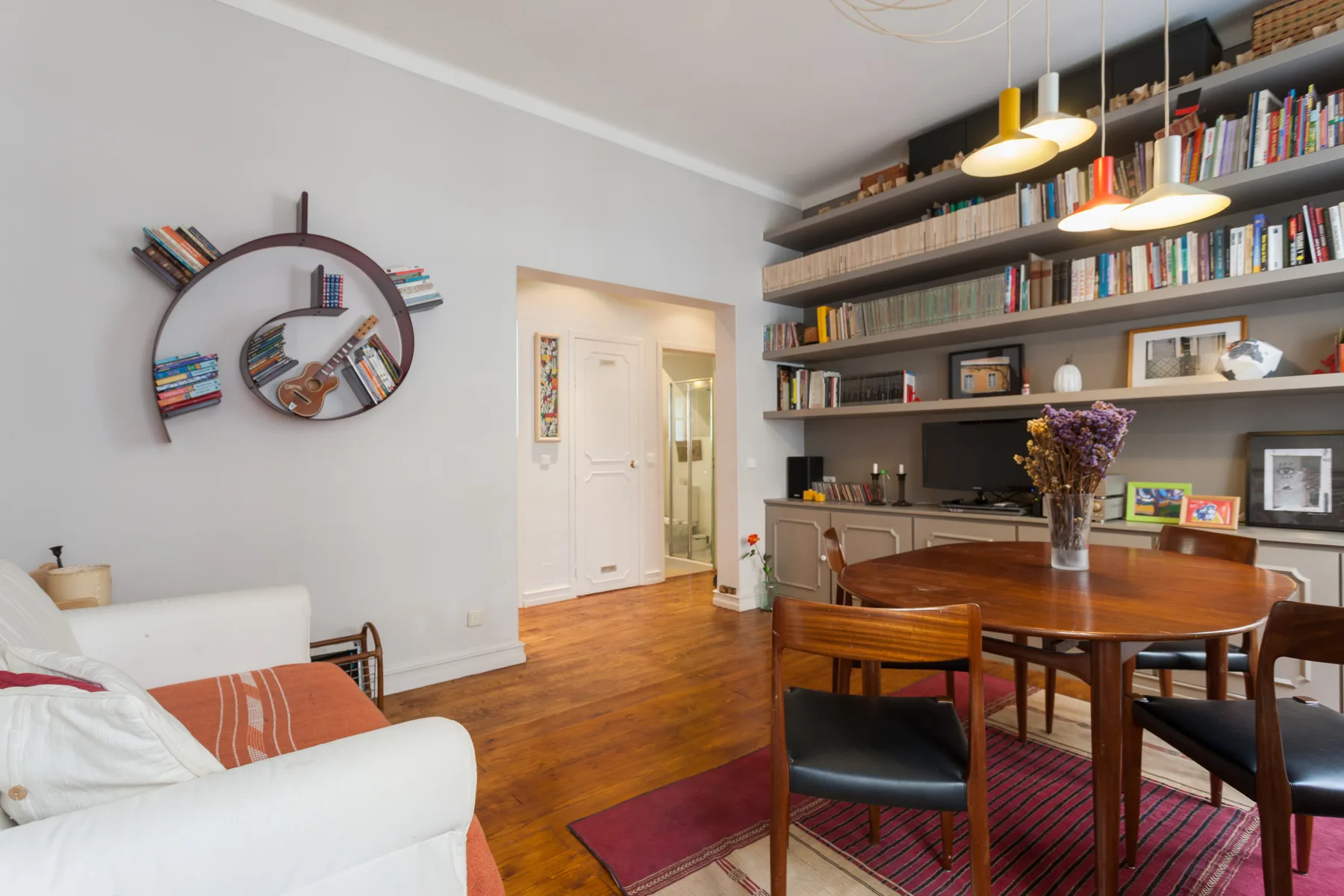 Una sala de estar y comedor con una gran estantería y una mesa de madera.