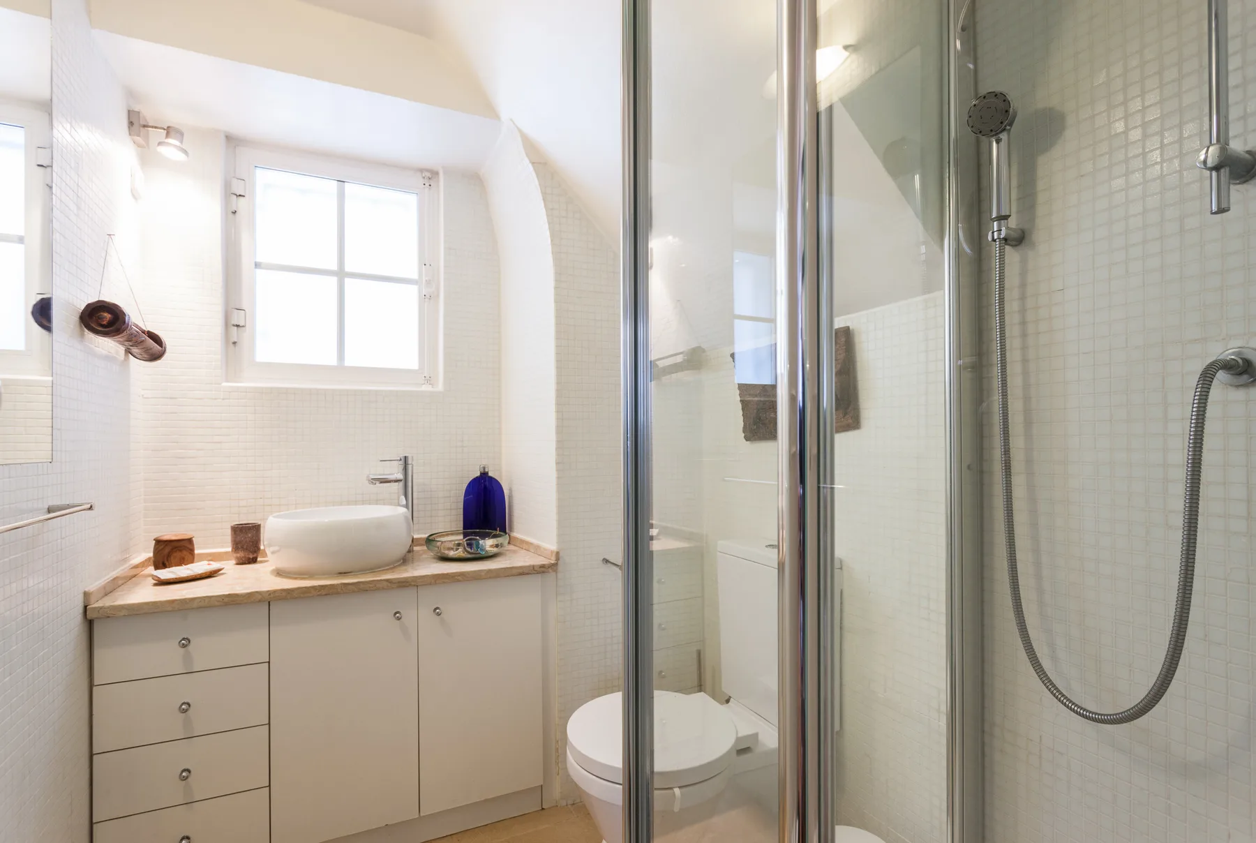 Un baño luminoso con lavabo, ventana y ducha.