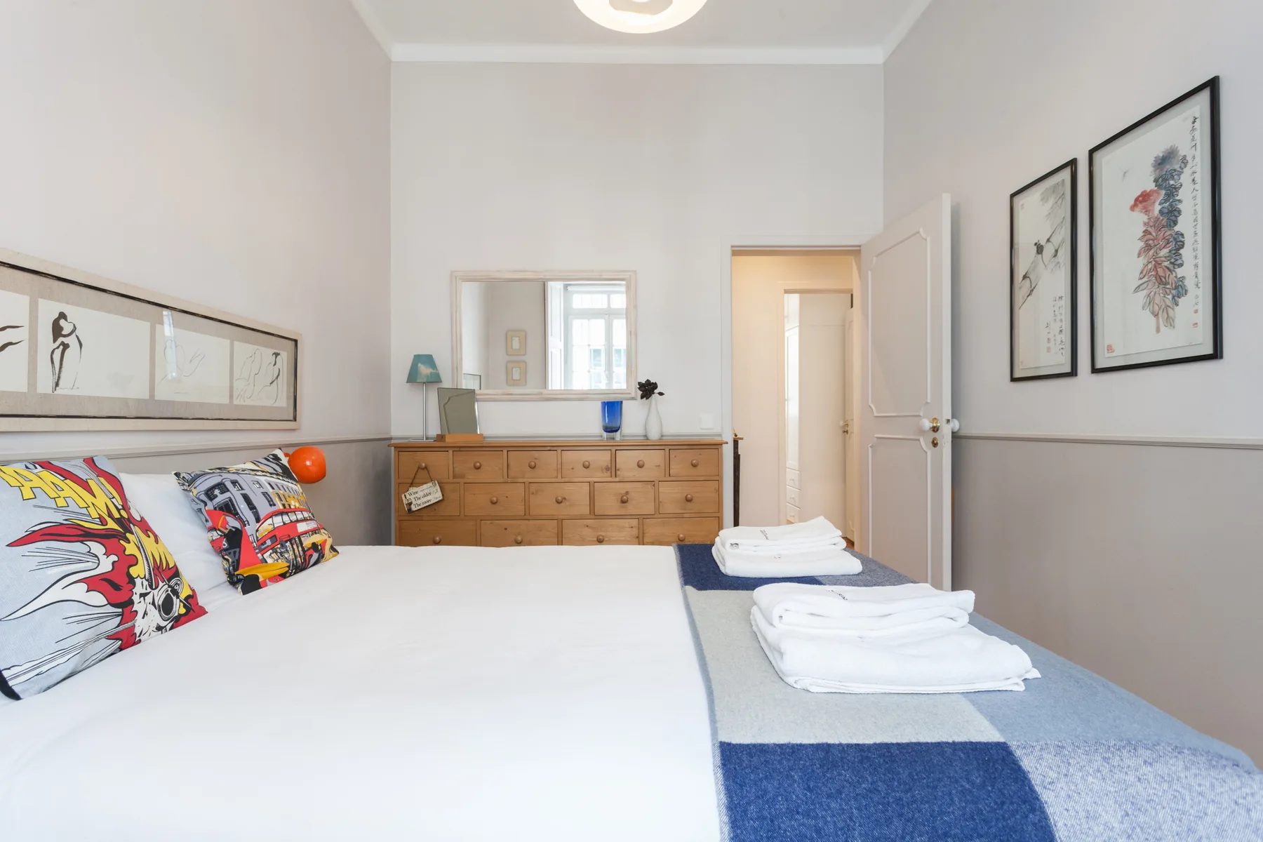 Un dormitorio con una cama, toallas dobladas y una cómoda de madera.
