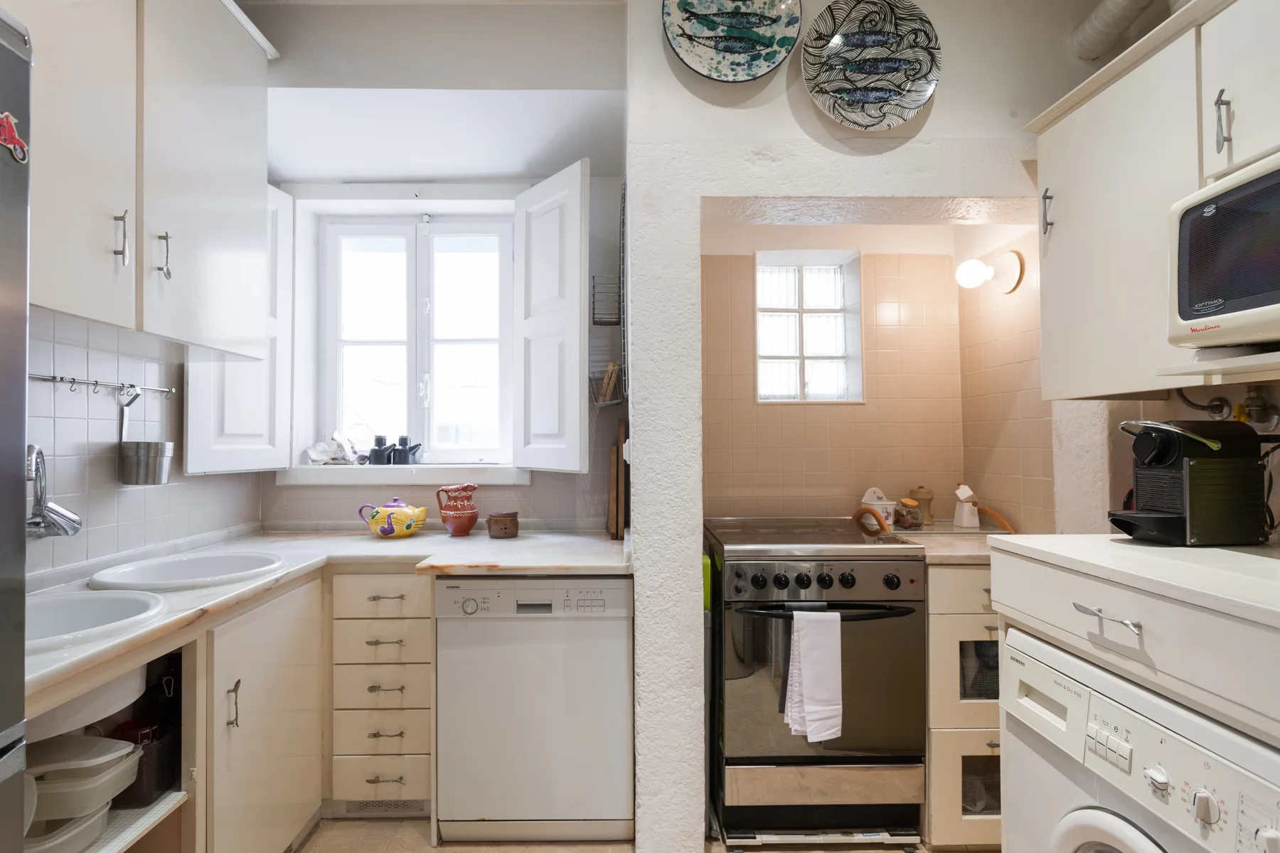 Una cocina compacta con armarios blancos, fregadero y electrodomésticos de cocina.