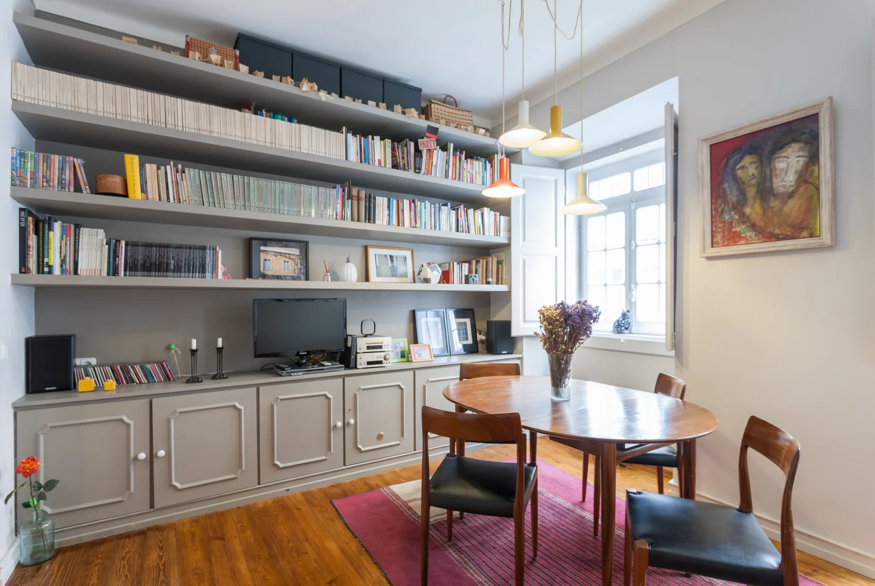 Comedor con una mesa de madera junto a una pared de estanterías.