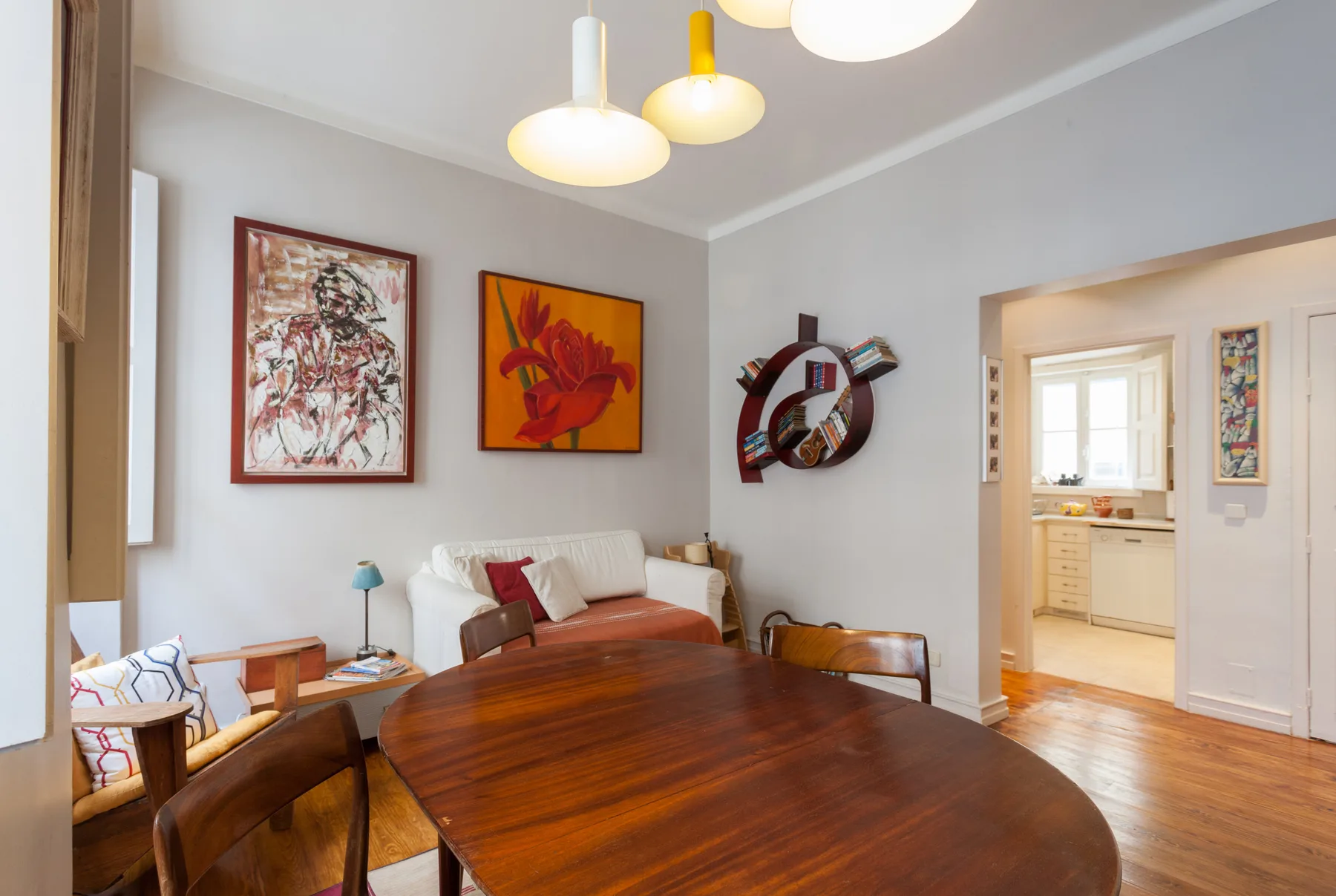 Una sala de estar con una mesa de comedor de madera, asientos y arte colorido en las paredes.