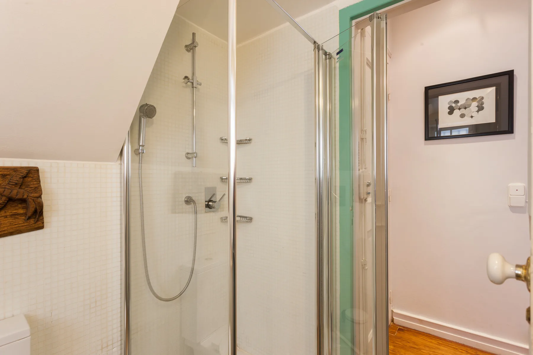 Un baño con una ducha de vidrio y una puerta abierta.
