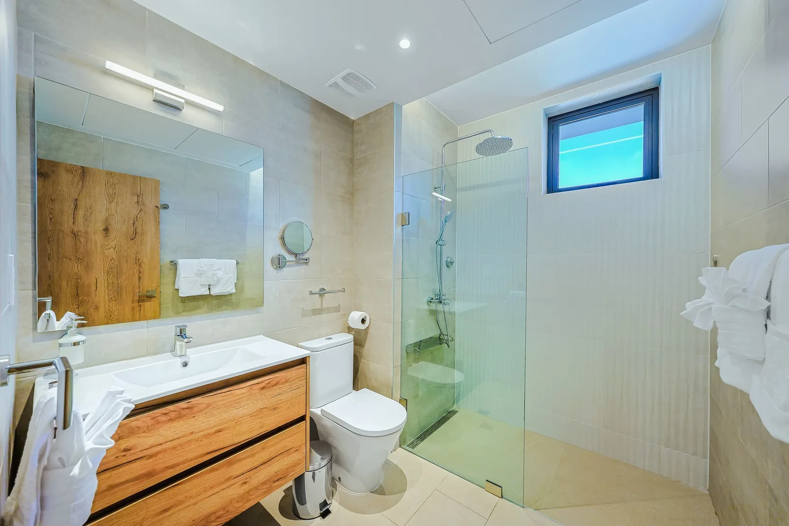 Step into your modern bathroom with sleek tiling, a spacious walk-in shower, and warm wood accents that add a touch of natural elegance to your getaway.