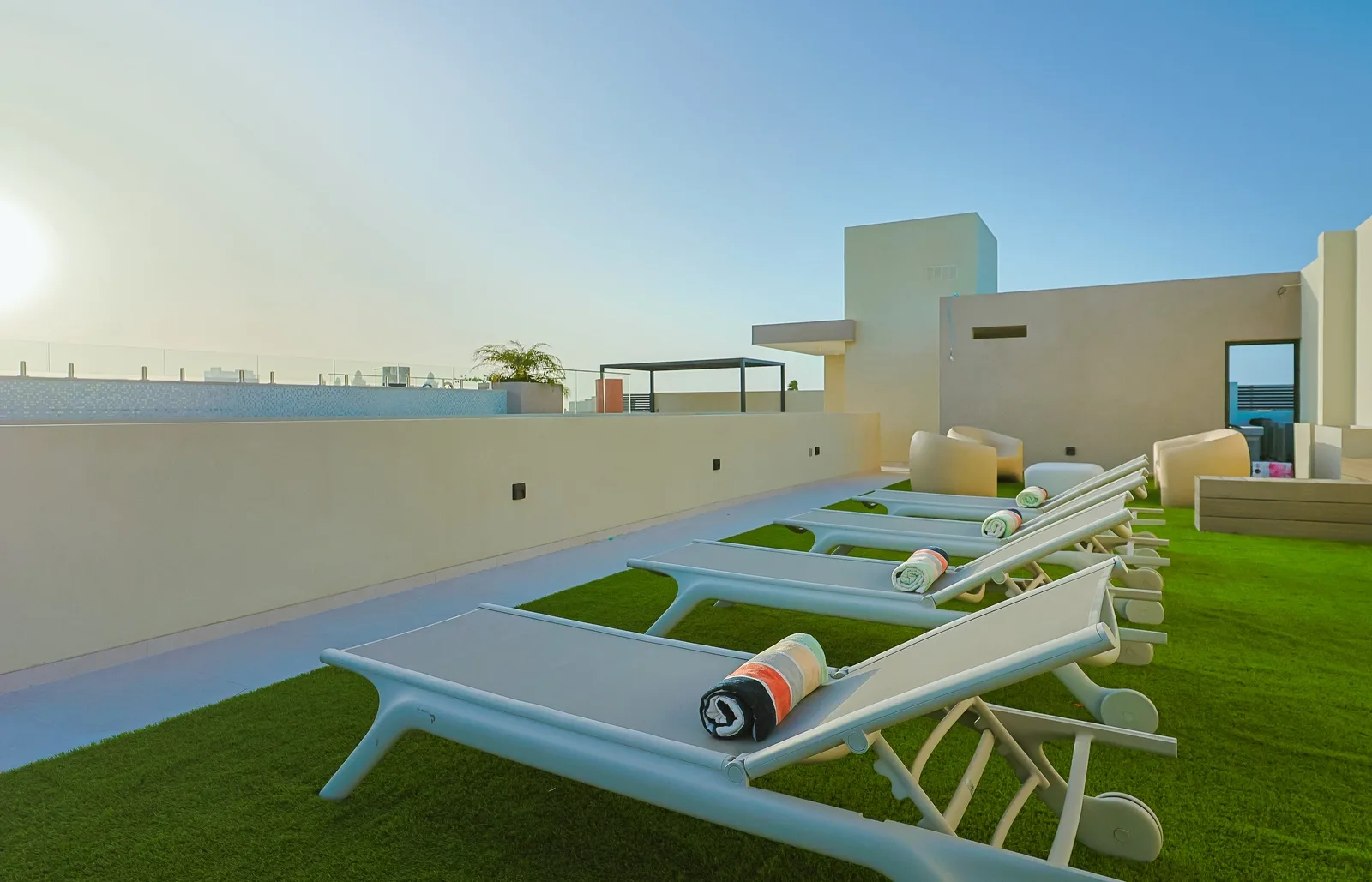 A stylish rooftop terrace featuring sun loungers offers a serene open-air retreat surrounded by contemporary design and tropical ambiance.