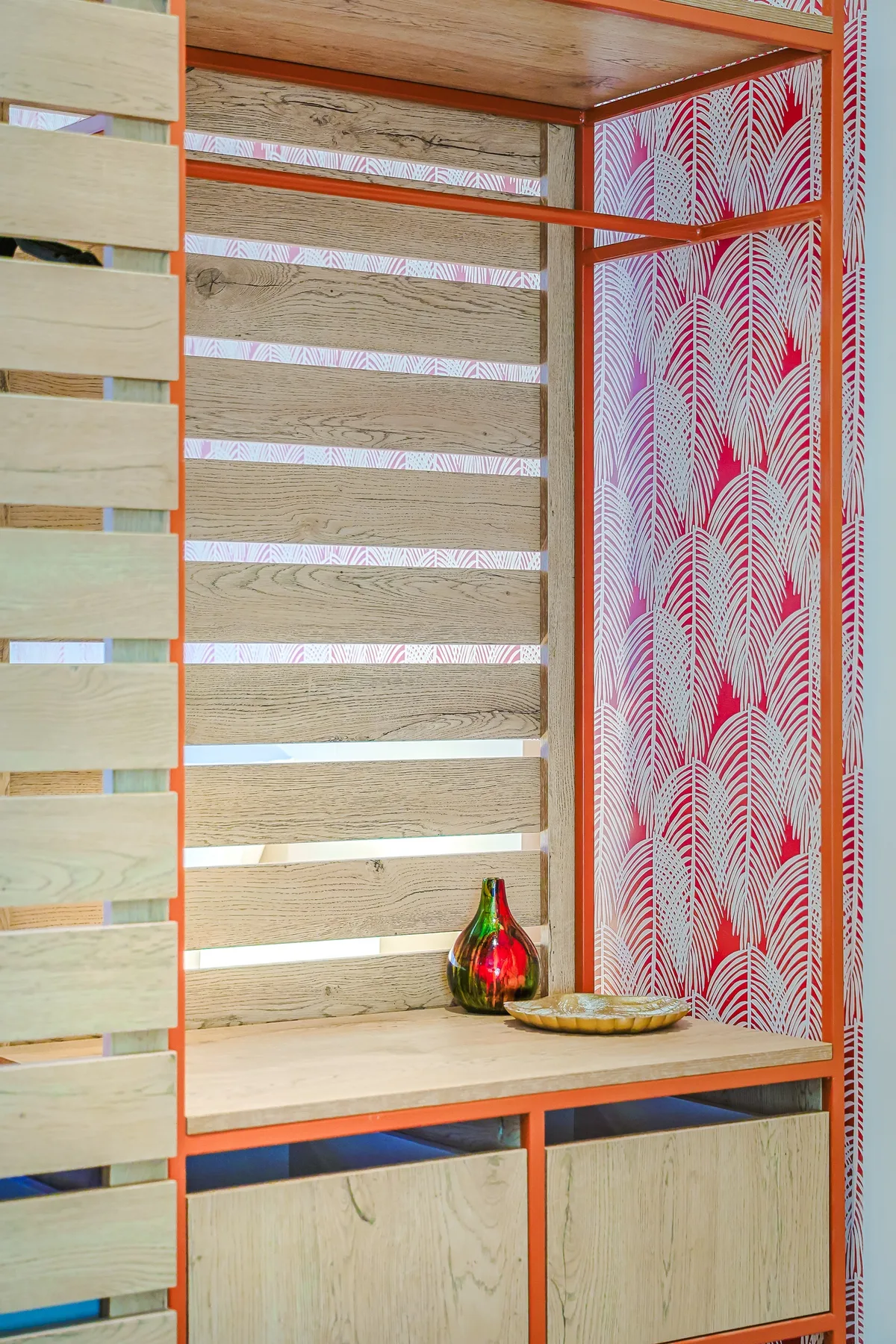 A cheerful wooden room divider with bold patterned wallpaper and orange metal framing adds a pop of personality to your stay.