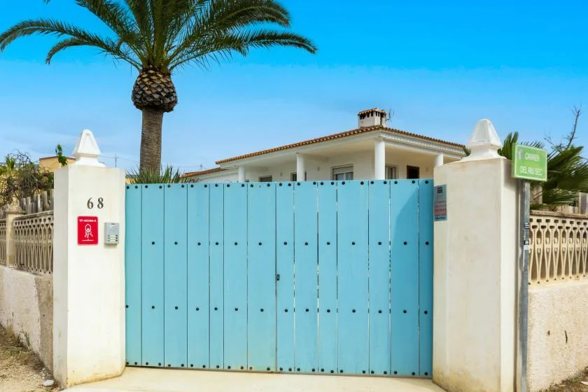 Una puerta azul da a un edificio blanco bajo un cielo despejado.