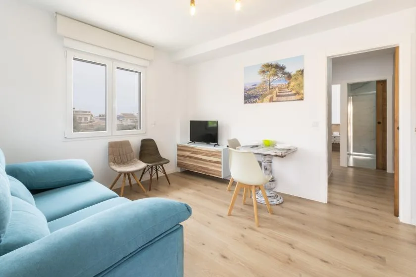A bright living and dining area with seating, a television, and a small table.