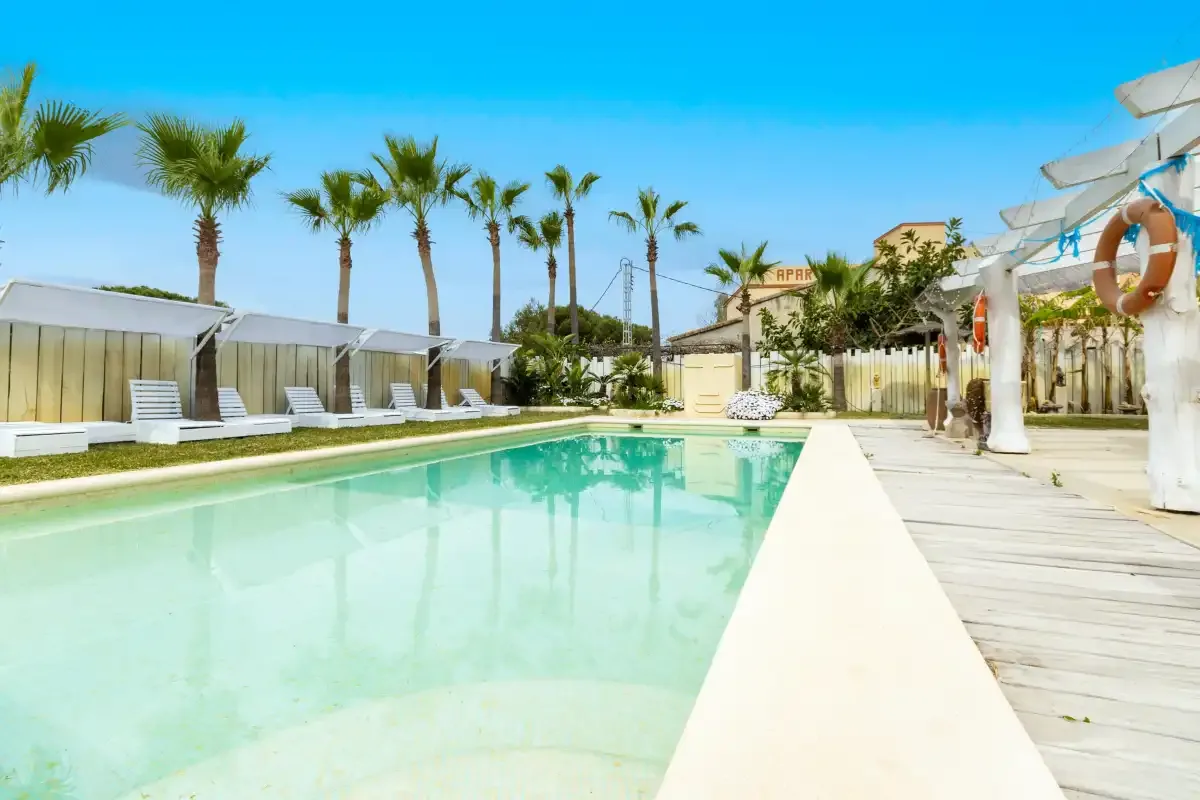 Una piscina al aire libre con palmeras y asientos de descanso.