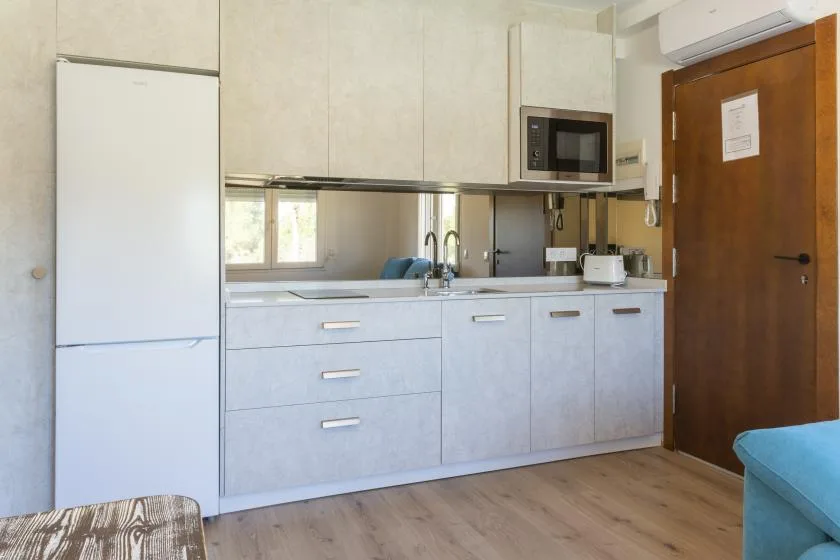 A compact kitchen with light cabinets, a refrigerator, and a countertop.