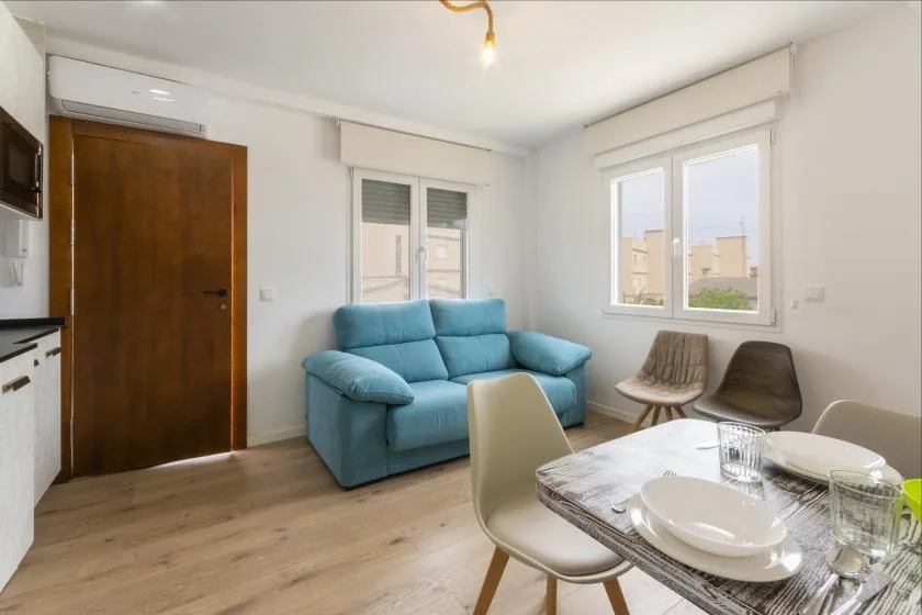 A bright living and dining area with blue seating and a set table.