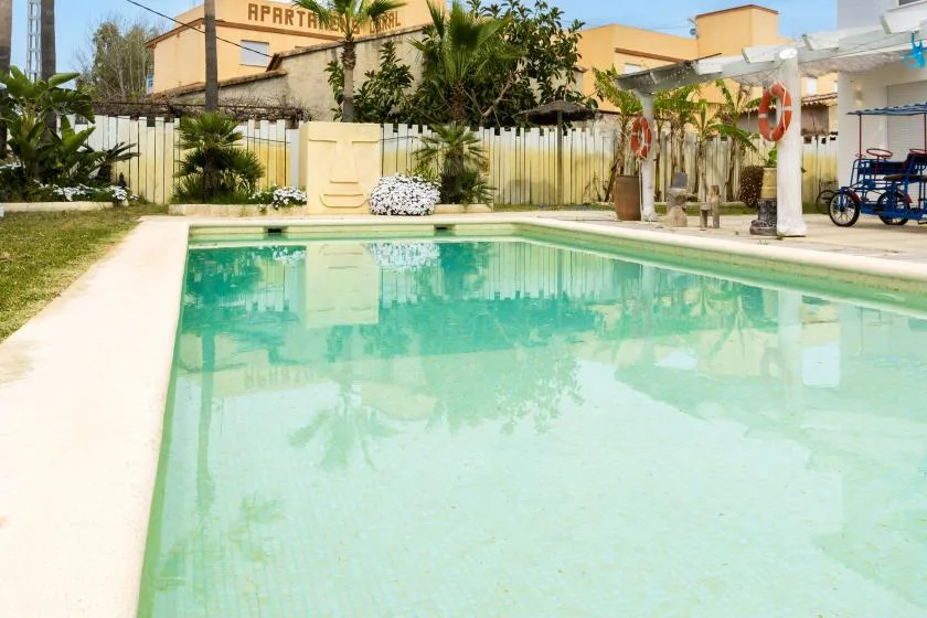 Una piscina al aire libre junto a una zona pavimentada y un jardín.