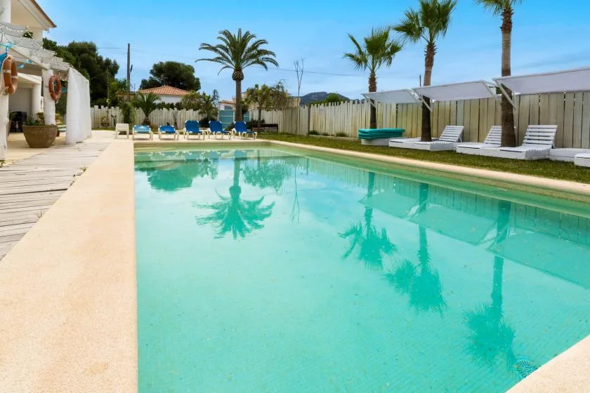 Una piscina con palmeras reflejadas en el agua.