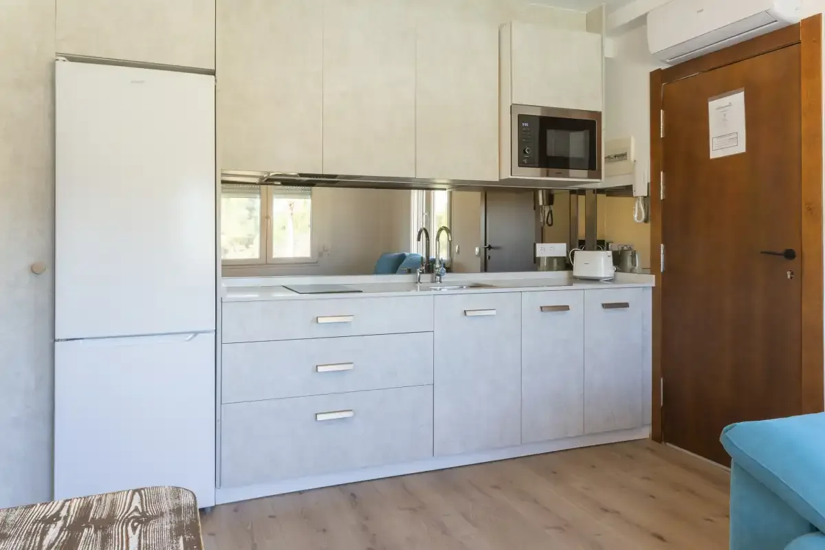 Una cocina con gabinetes blancos, un refrigerador y una encimera.