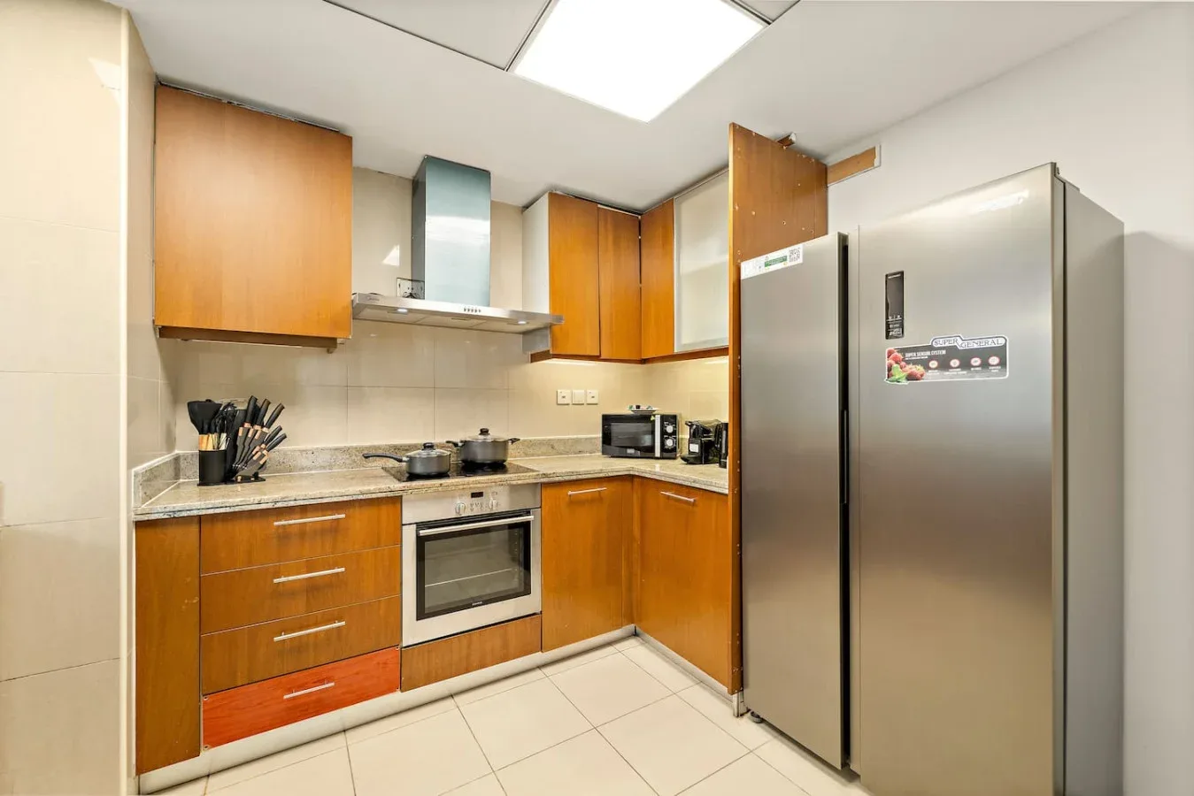 Una cocina con armarios de madera, una encimera y un refrigerador de acero inoxidable.