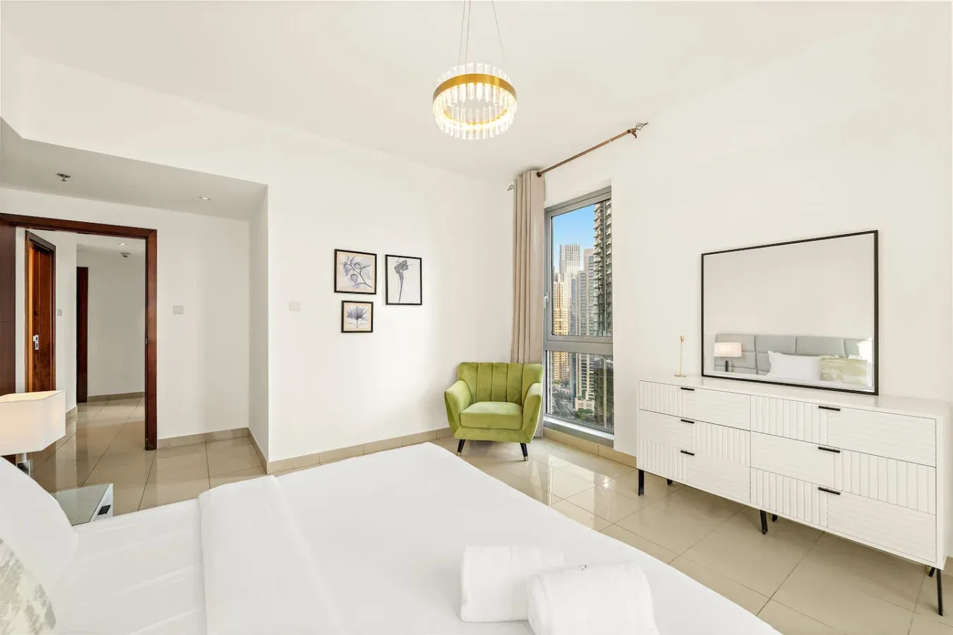 Un dormitorio luminoso con una cama, un sillón verde y una ventana grande.