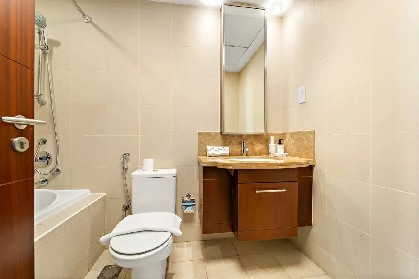 Un baño con bañera, inodoro y lavabo bajo un espejo de pared.