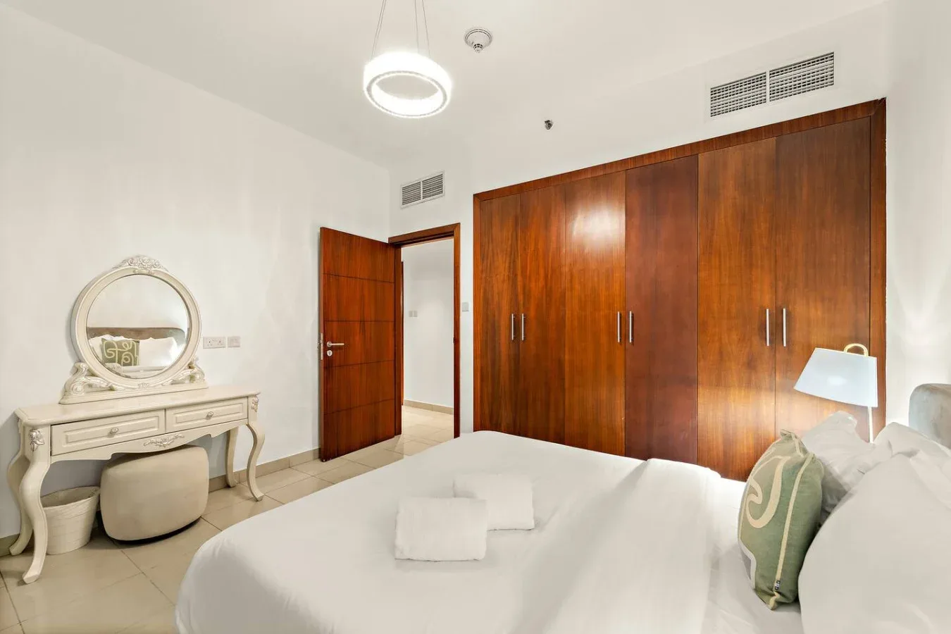 Un dormitorio con una cama blanca, armarios de madera y un tocador.