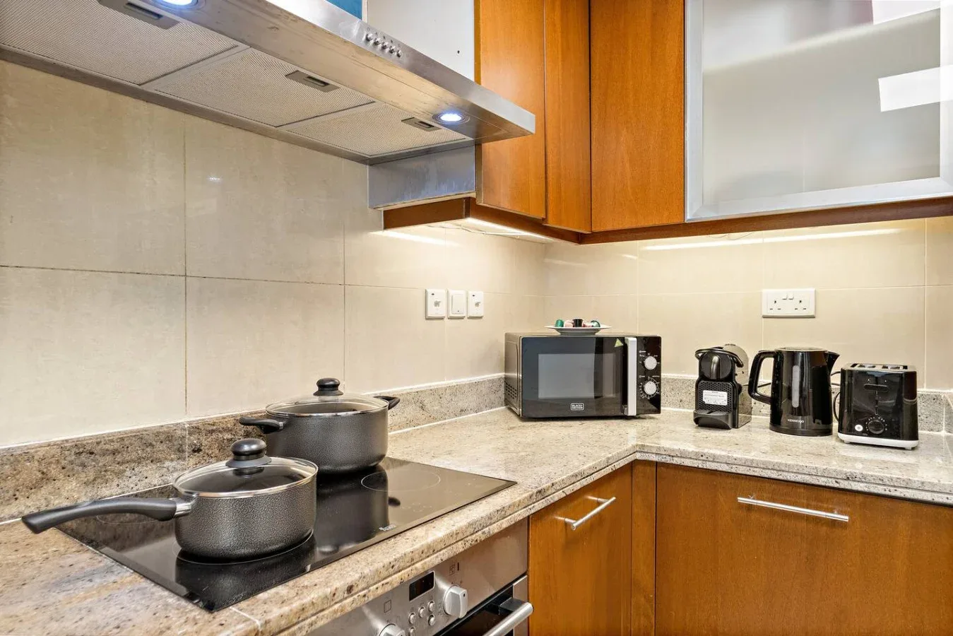 Una cocina con una estufa, ollas y electrodomésticos sobre la encimera.
