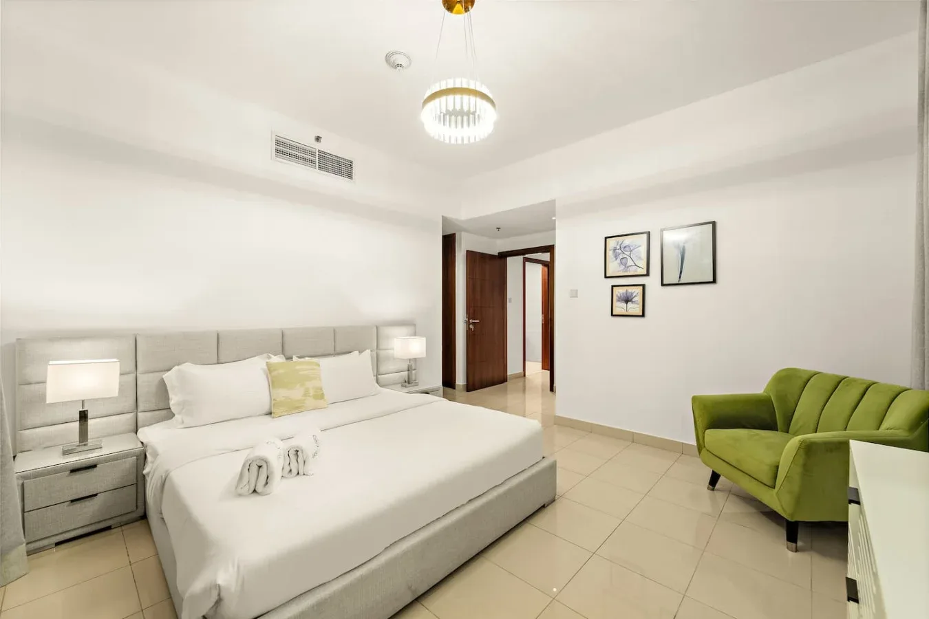 Un dormitorio luminoso con una cama grande y un asiento tapizado verde.