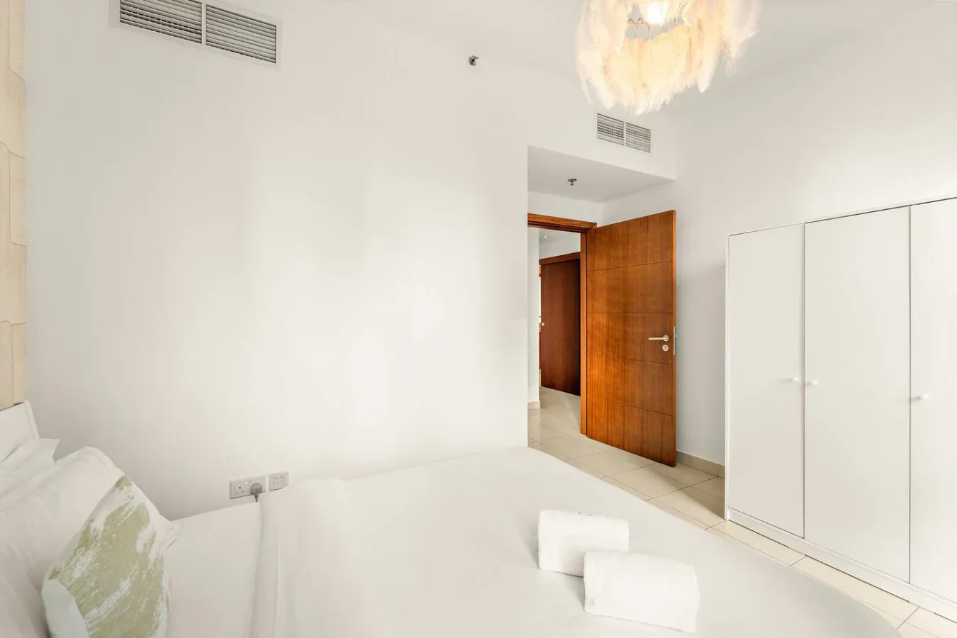 Un dormitorio luminoso con ropa de cama blanca y una puerta de madera.