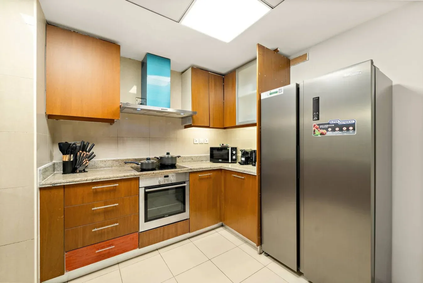 Una cocina moderna con gabinetes de madera, una encimera y un refrigerador grande.