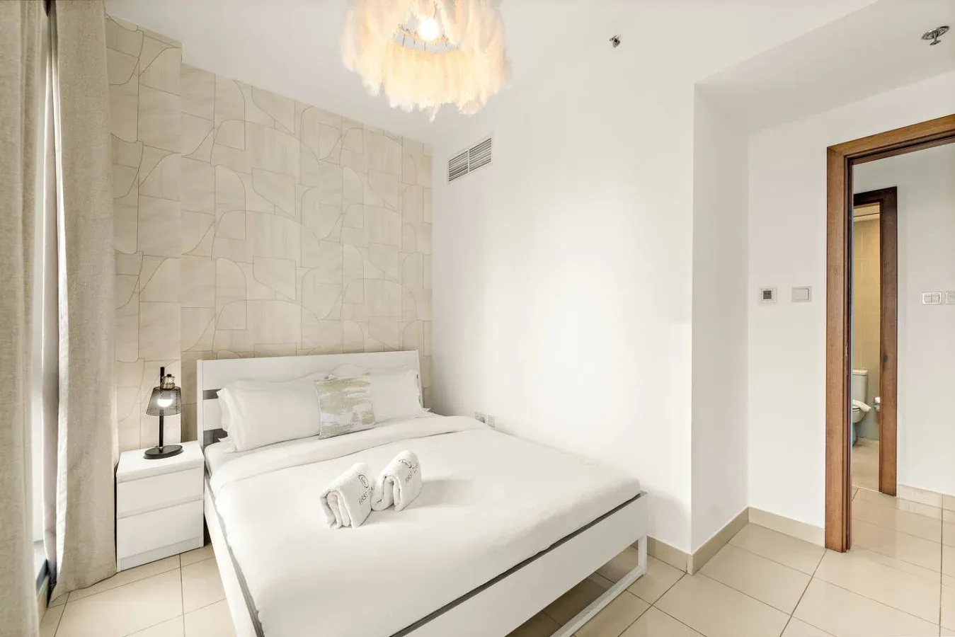 Un dormitorio luminoso con una cama bien hecha y una mesita de noche.