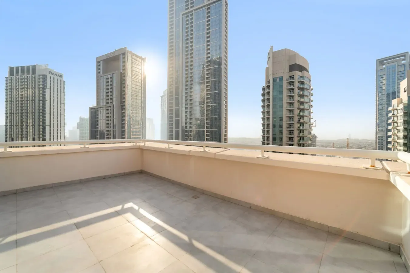 Una terraza en la azotea con un muro bajo ofrece vistas de edificios altos cercanos.