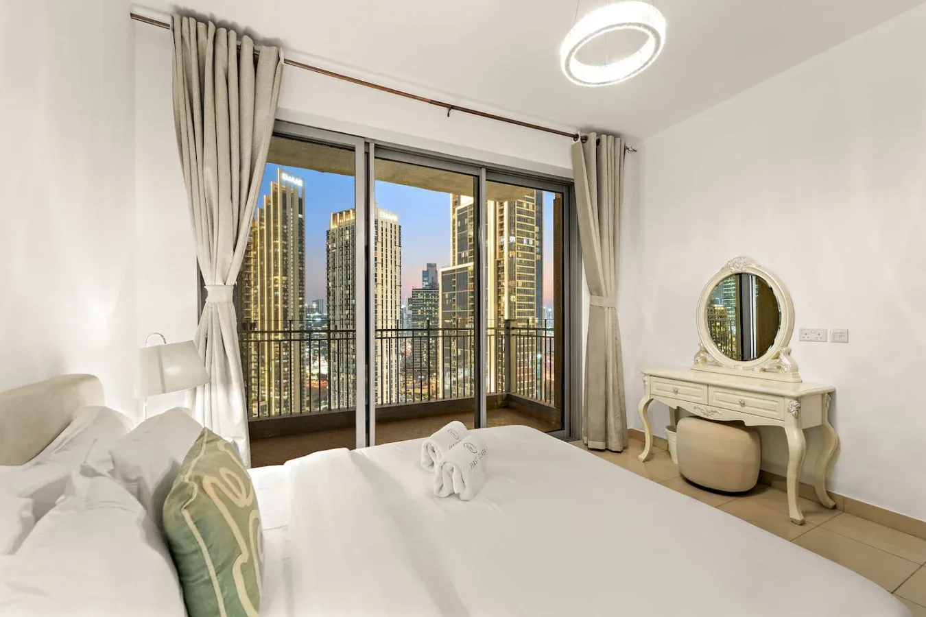 Un dormitorio con una cama frente a puertas de cristal y vistas a la ciudad.