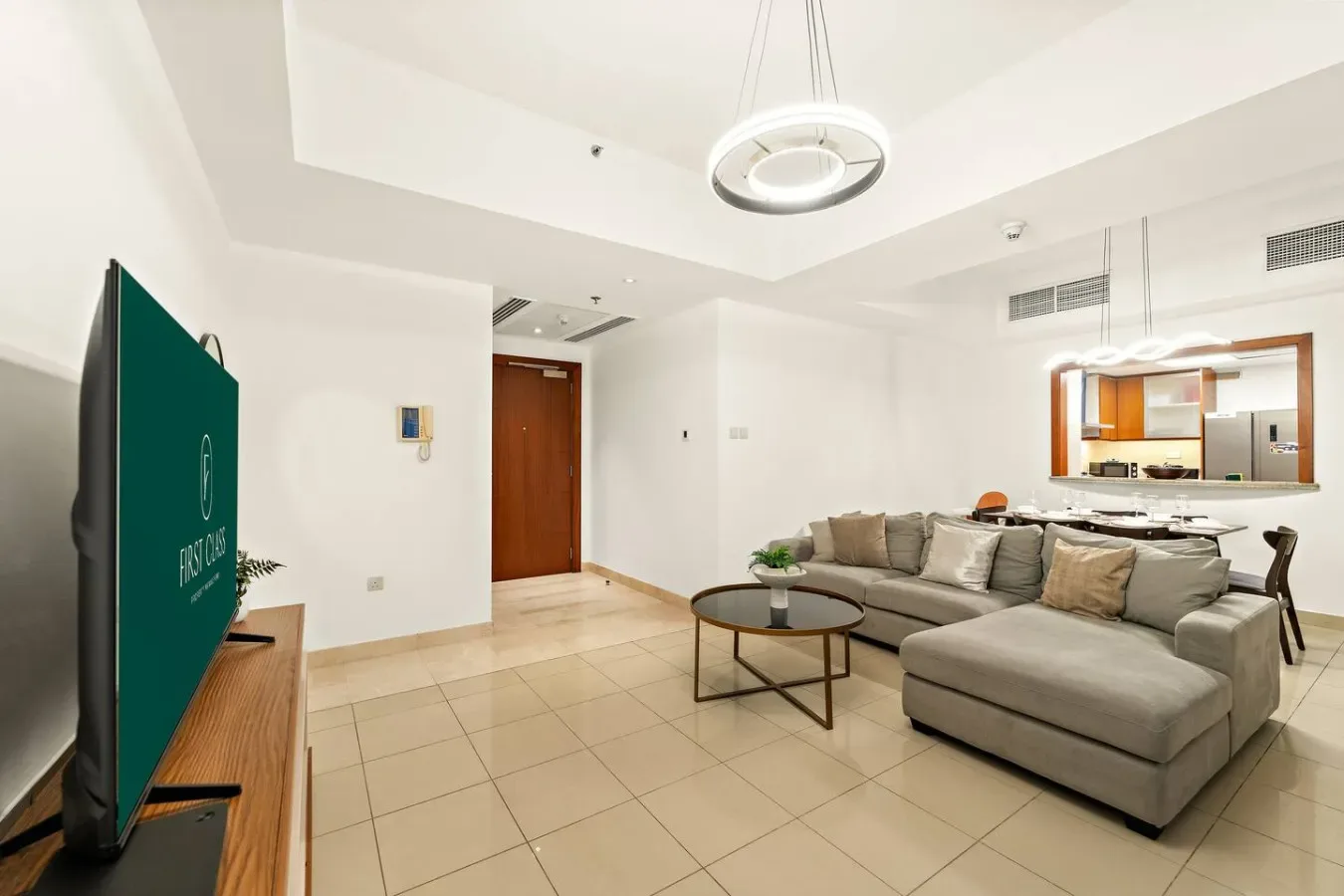Una sala luminosa con asientos seccionales y una cocina abierta al fondo.