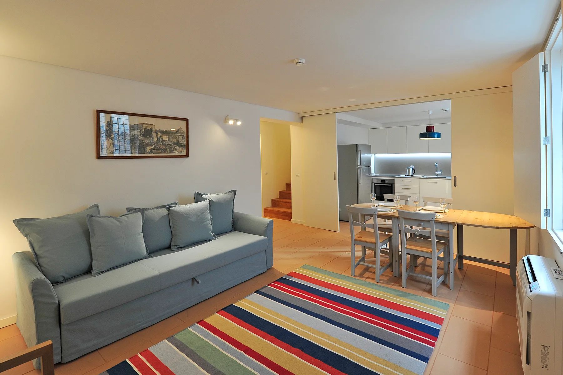 Living room with seating, a dining table, and an open kitchen.