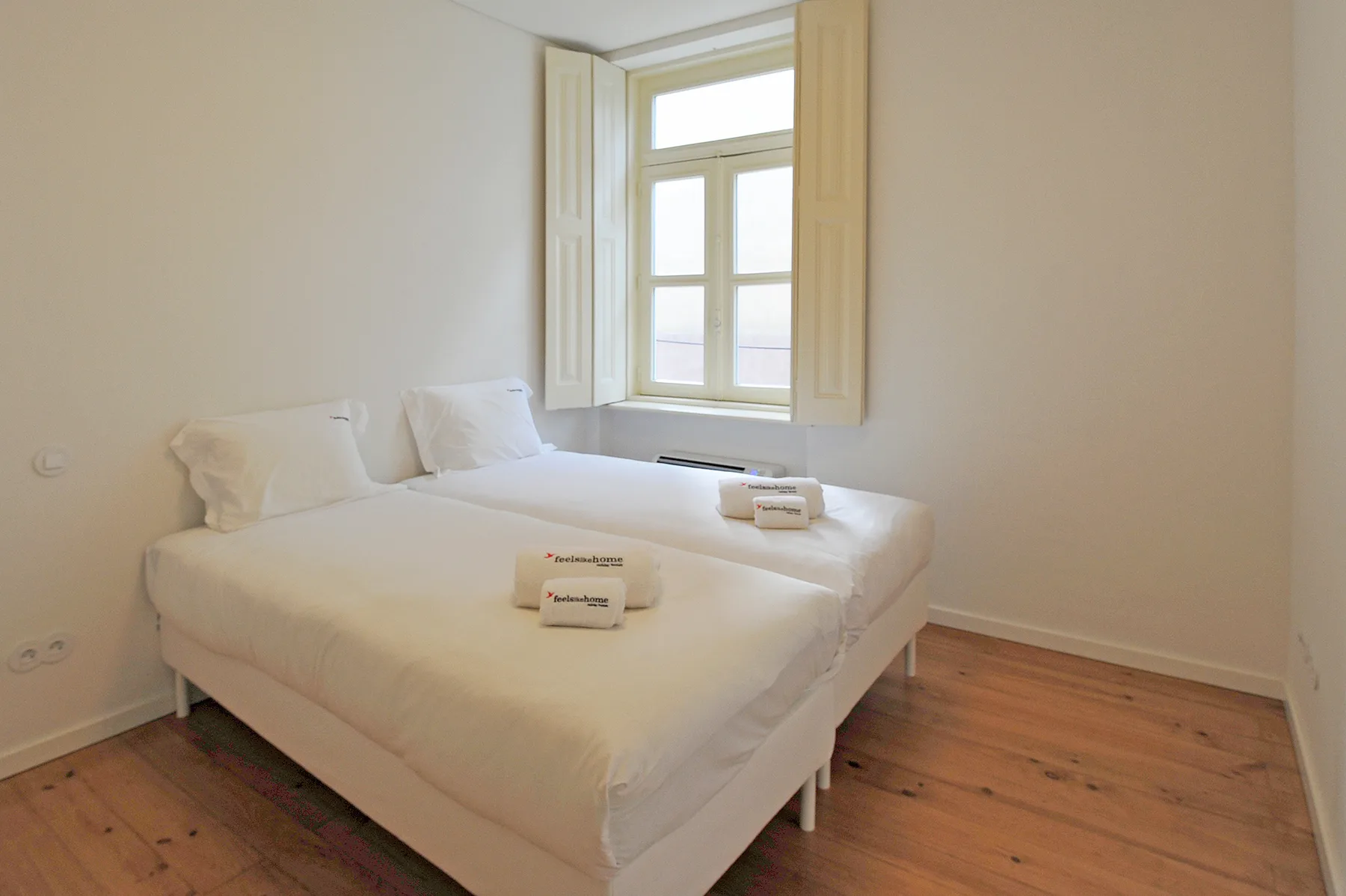 A bright bedroom with a bed beneath an open window.