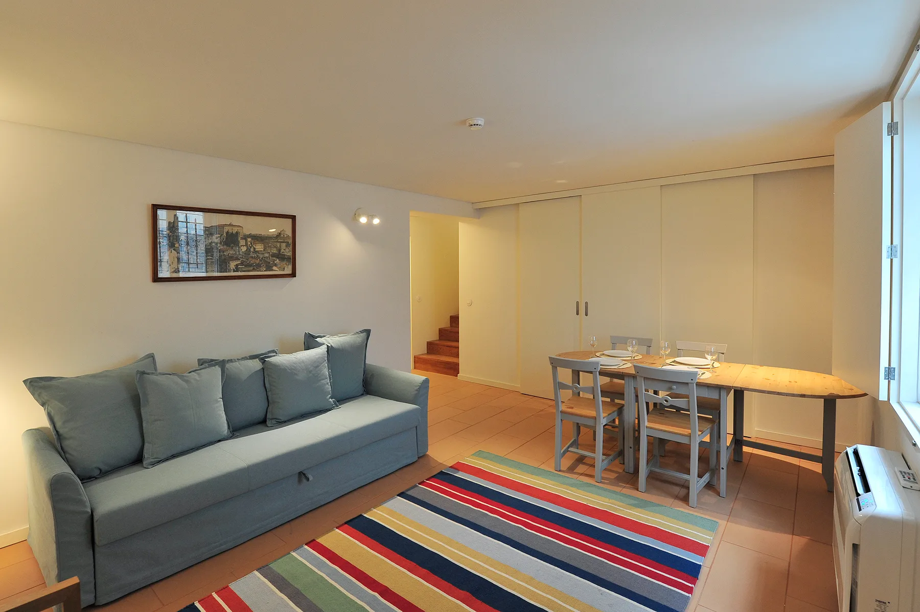 A living and dining area with seating, a table, and a colorful striped rug.