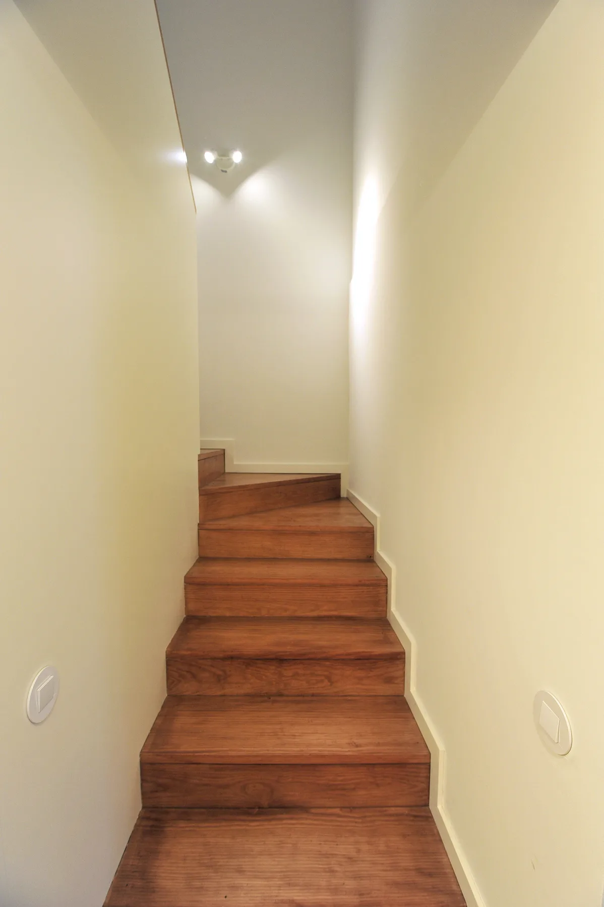 A narrow indoor staircase with wooden steps leads to a small landing.