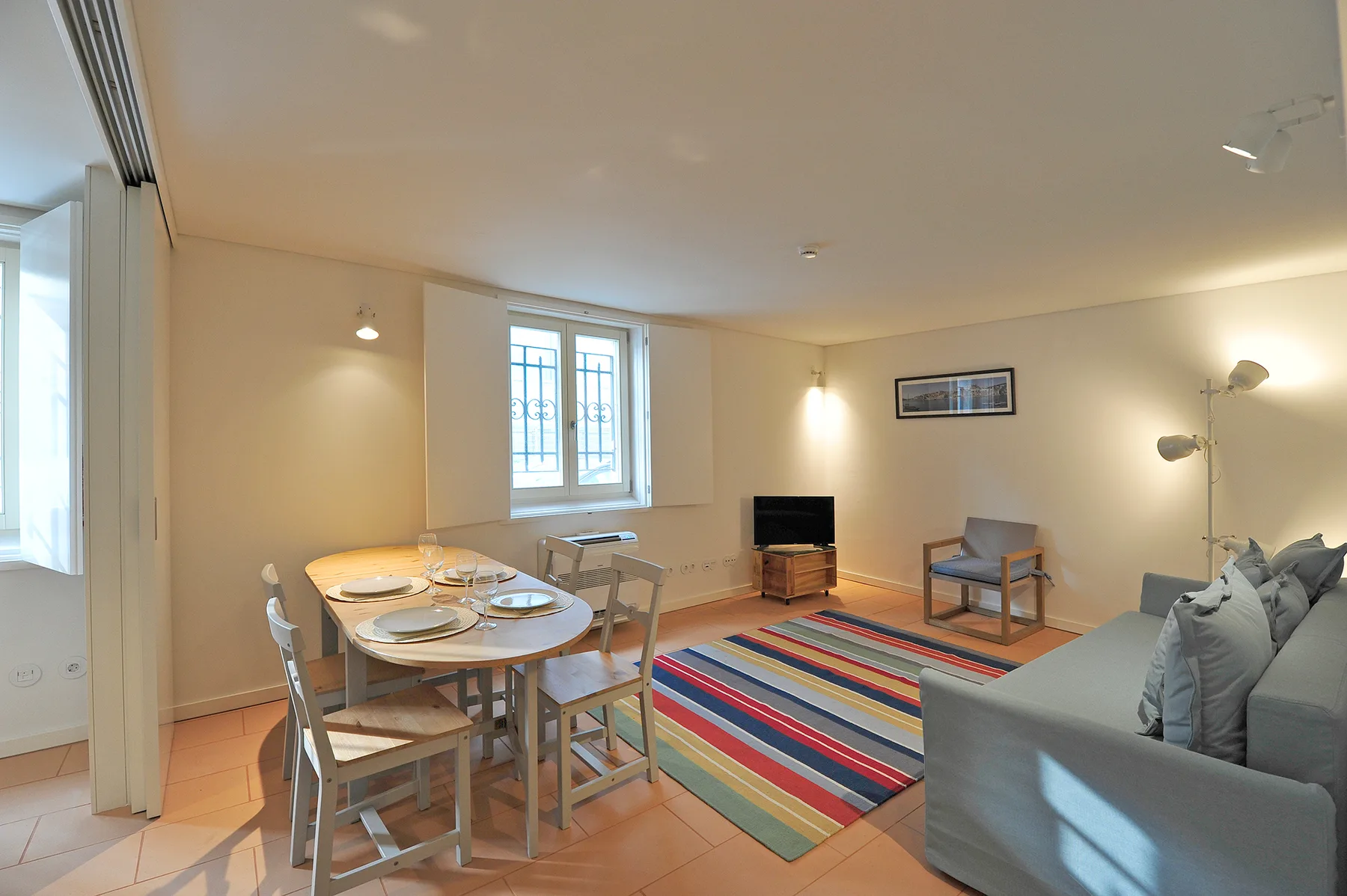 A living and dining area with a dining table, seating, and a colorful rug.