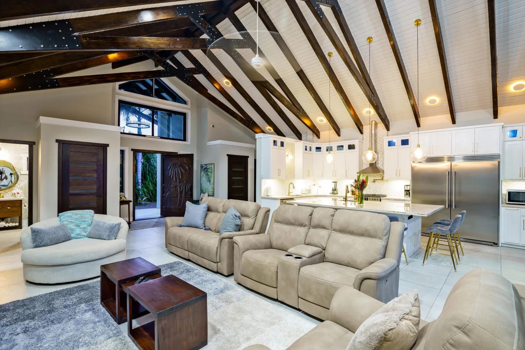 An open living room with cushioned seating and a bright kitchen.