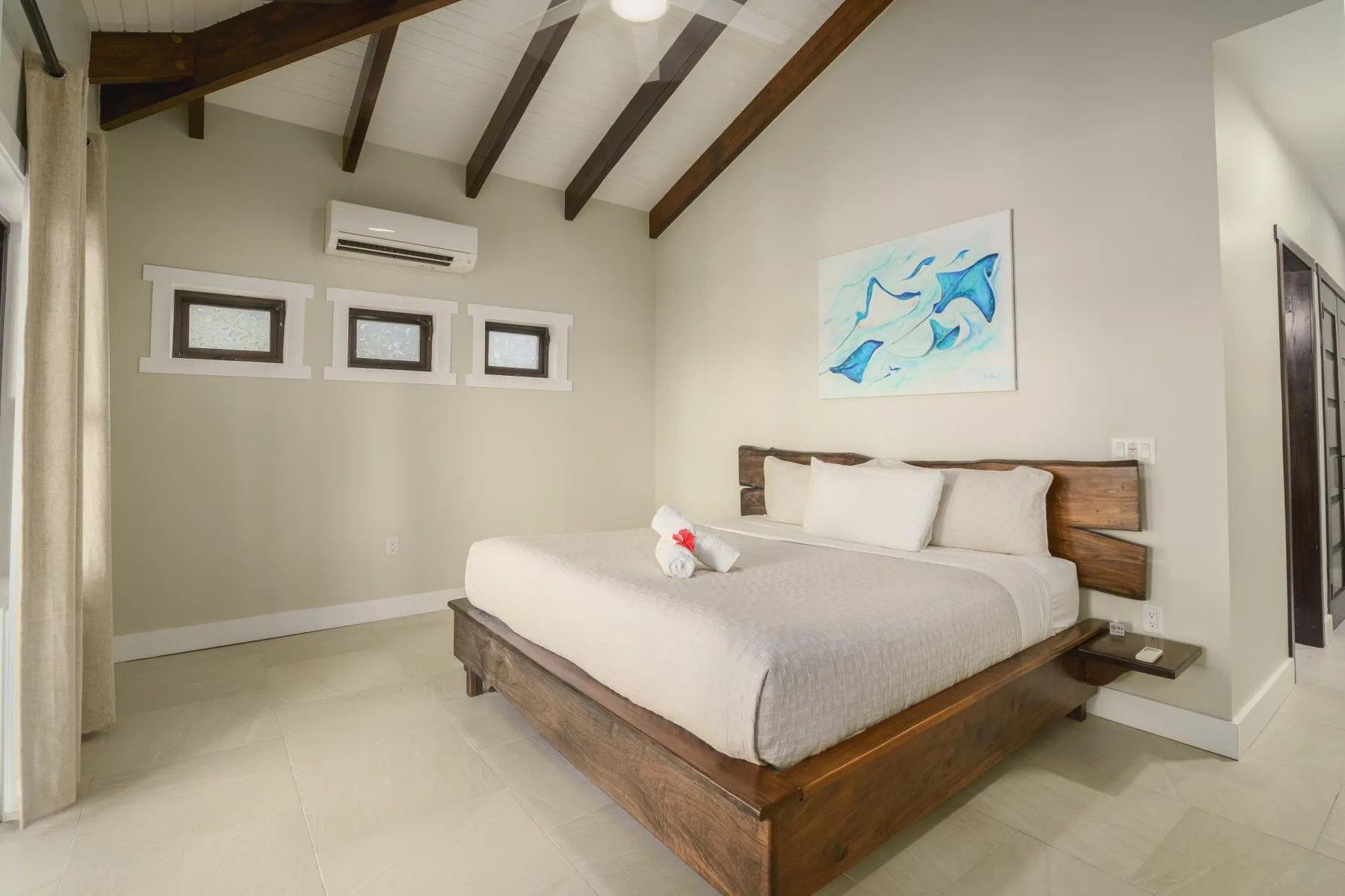 A bedroom with a wooden bed, white bedding, and exposed ceiling beams.