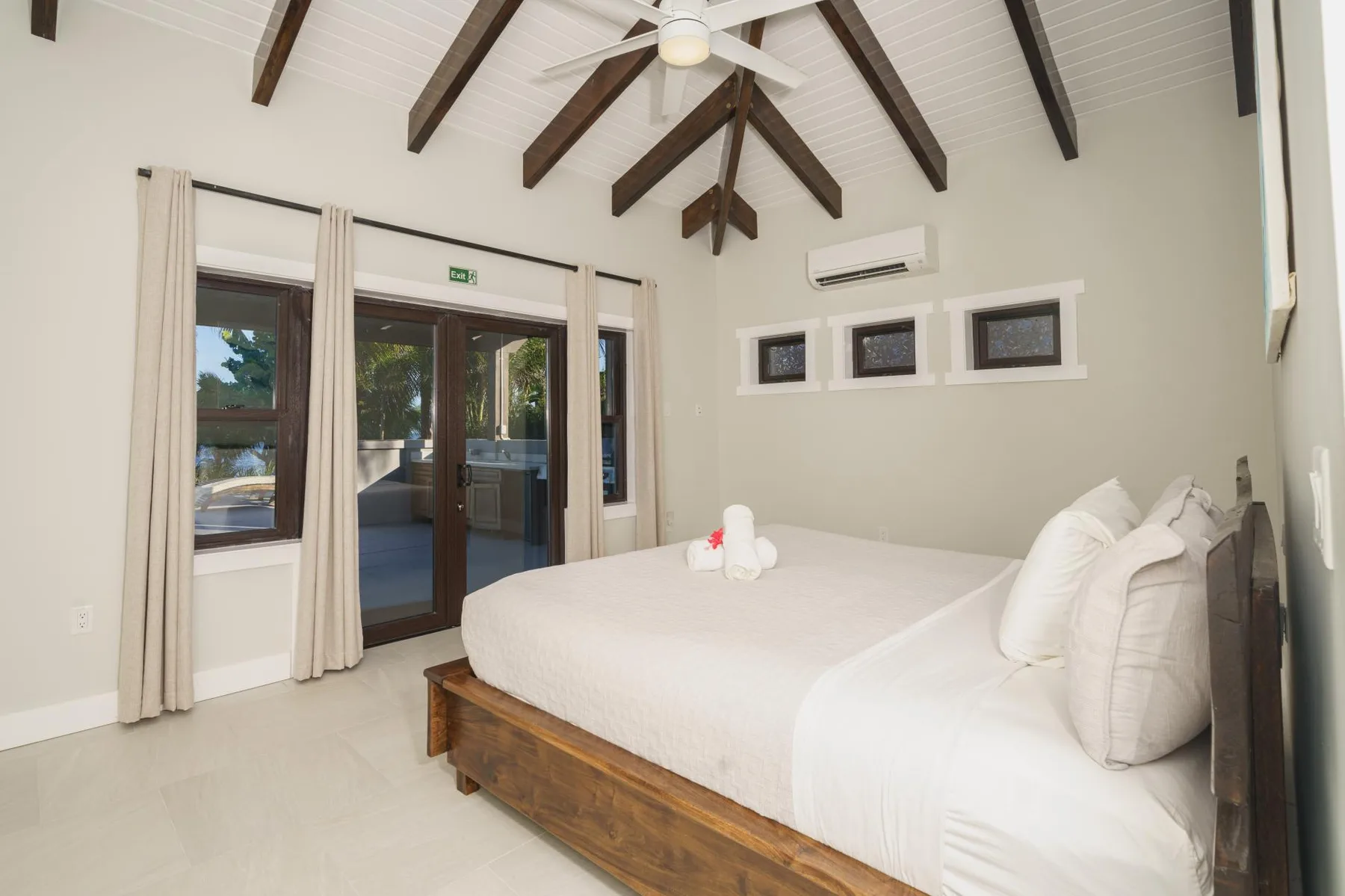 A bright bedroom with a large bed and sliding glass doors opening onto a patio.