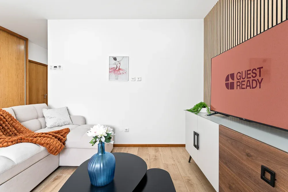A modern living room with seating and a television on a media console.
