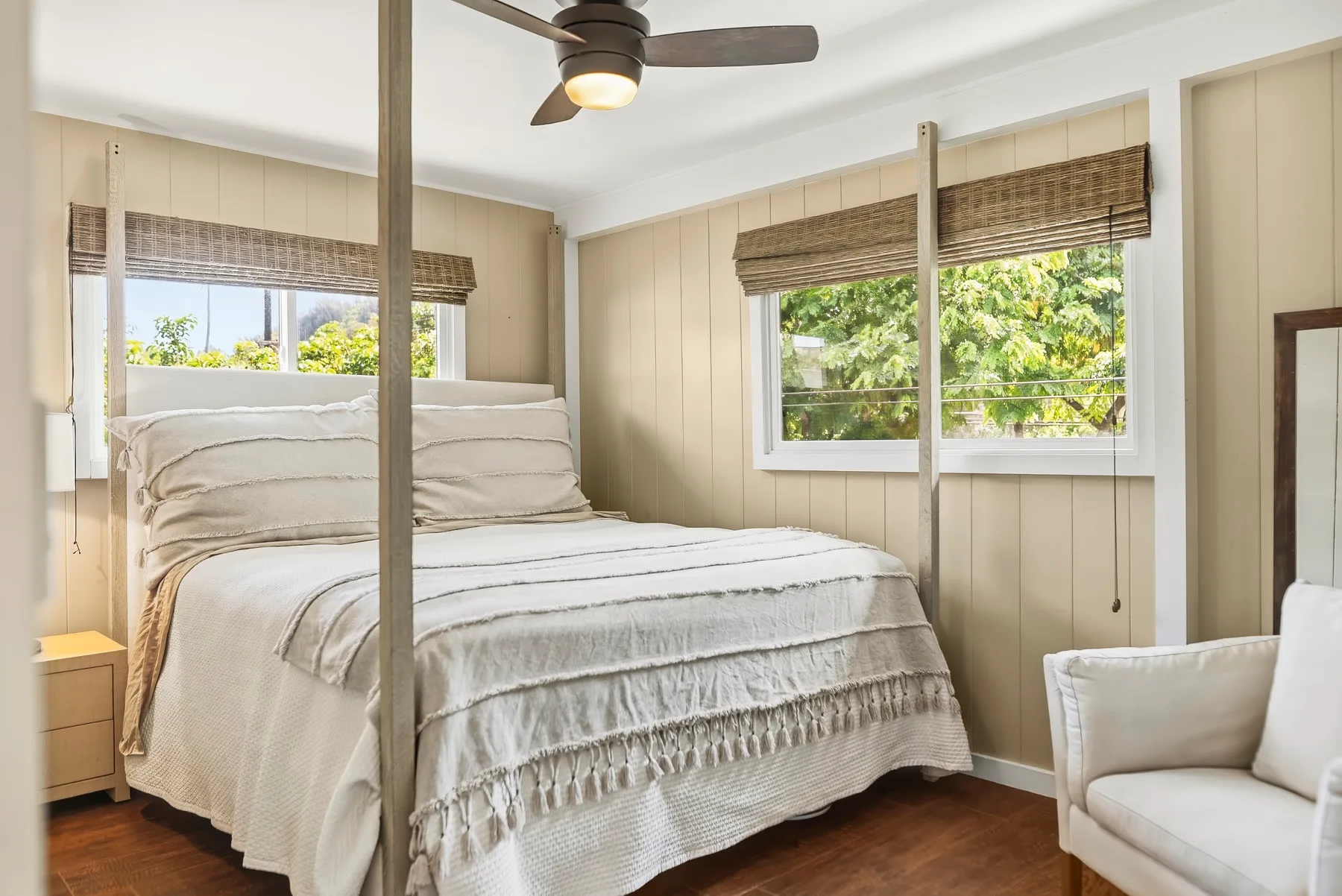 Un dormitorio con una cama bien tendida, ventanas y un ventilador de techo.