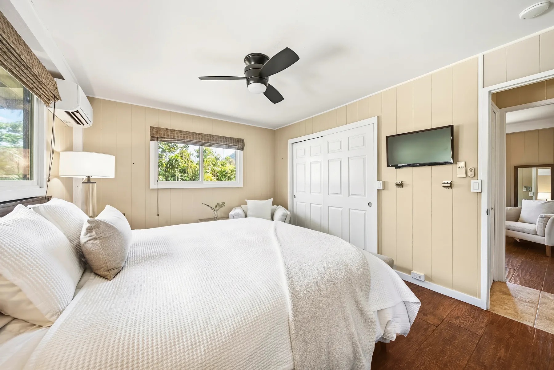 Un dormitorio con una cama, ventanas y un ventilador de techo.