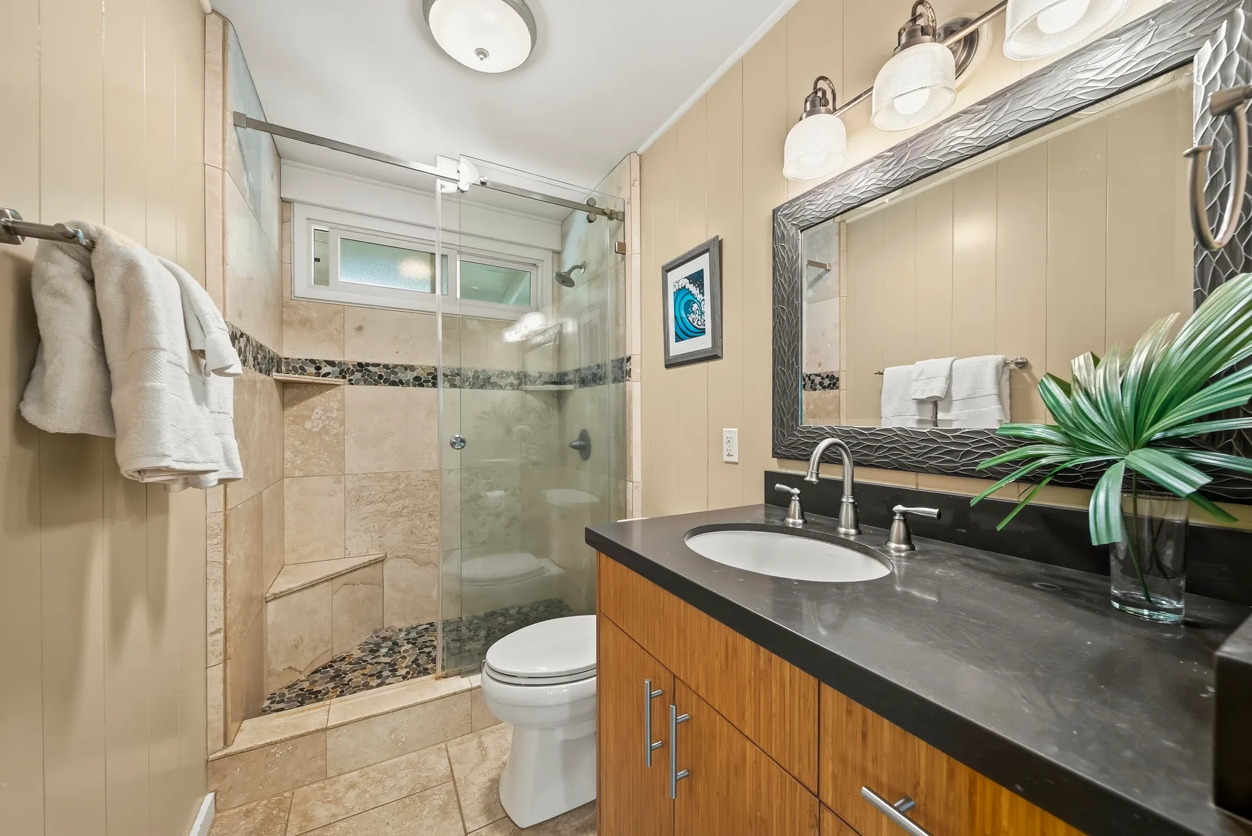 Un baño con ducha de vidrio, inodoro y tocador con lavabo.
