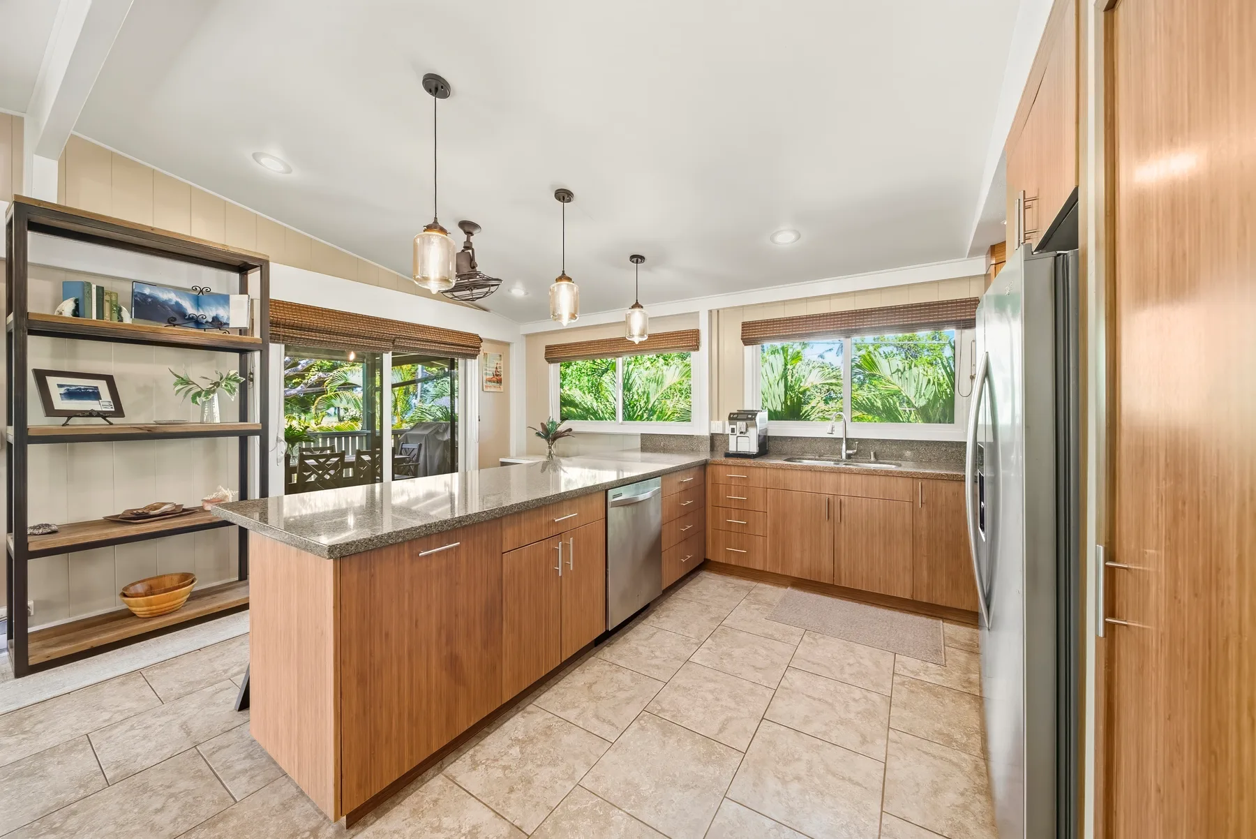 Una cocina amplia con una isla central, gabinetes de madera y ventanas grandes.