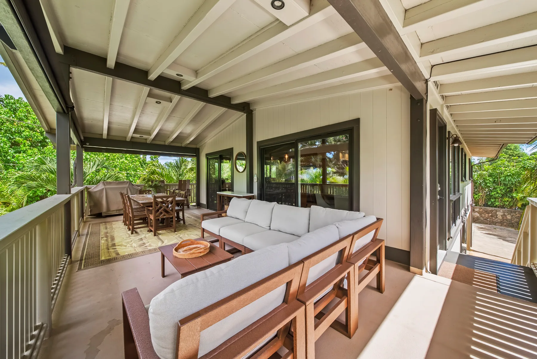Una zona exterior cubierta con mesa de comedor y asientos acolchados.
