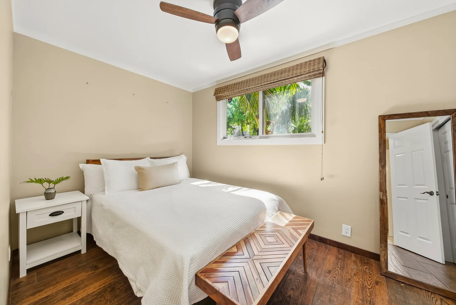 Un dormitorio con una cama tendida, una ventana y un ventilador de techo.
