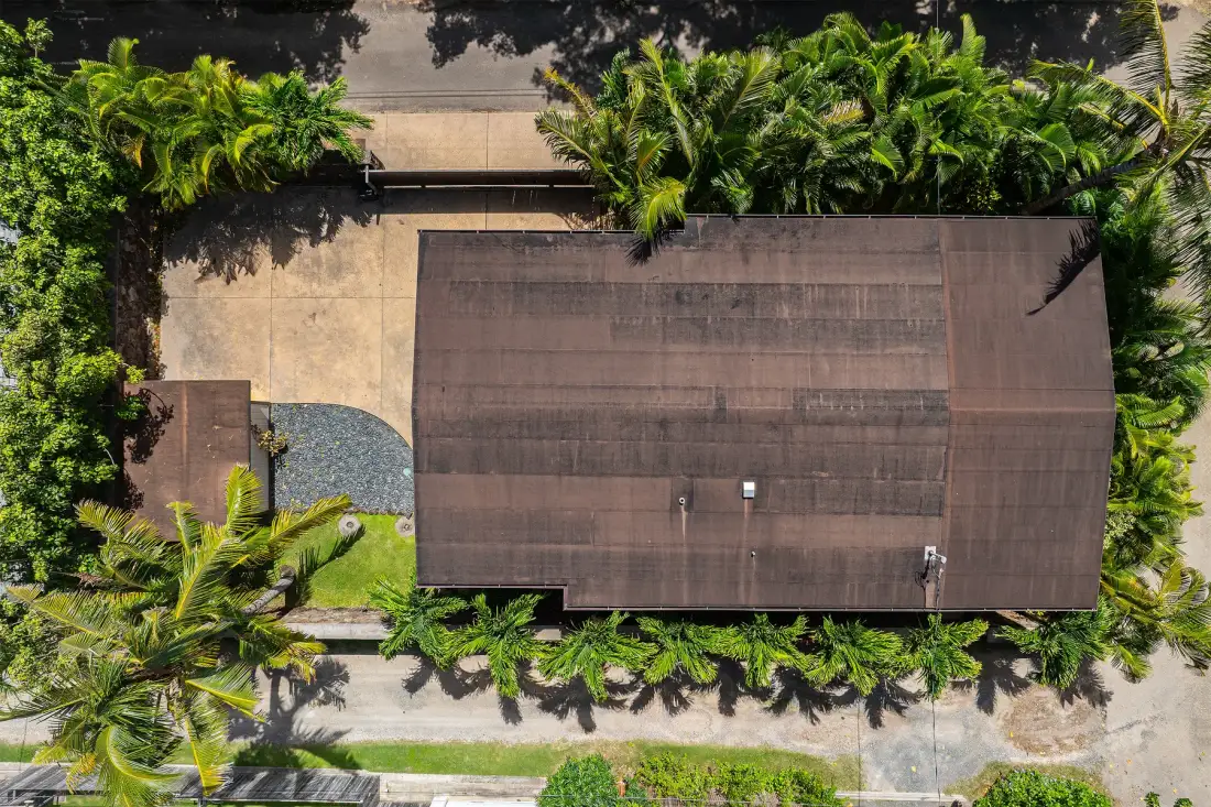 Una vista aérea muestra un techo rectangular grande rodeado de vegetación tropical densa.