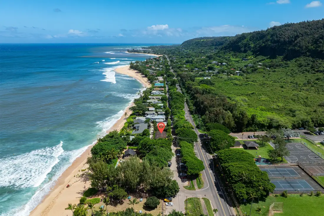 Vista aérea de una costa tropical con playa, océano y una carretera cercana.